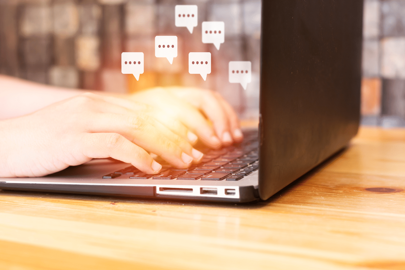 Photo of hands typing on a laptop with chat bubbles hovering above, signifying the use of AI chat in TrialKit