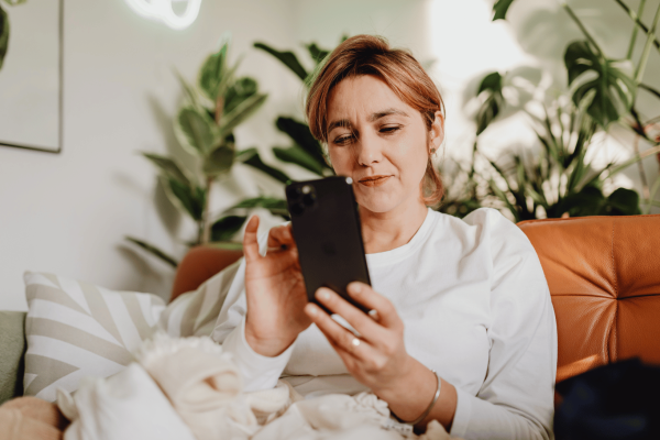 Woman using smartphone at home to participate in clinical trial