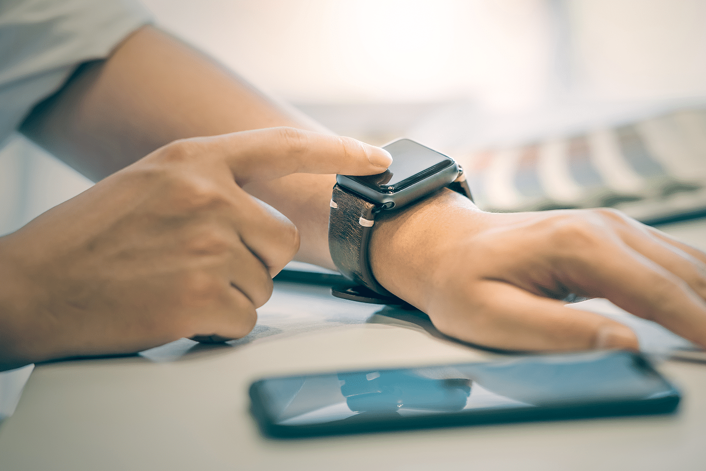 Person wearing a smartwatch with their smartphone nearby