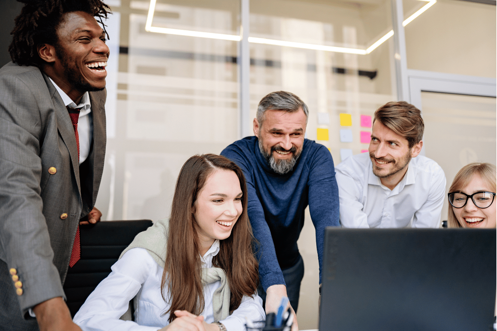 team of professionals smile reviewing something on a computer screen