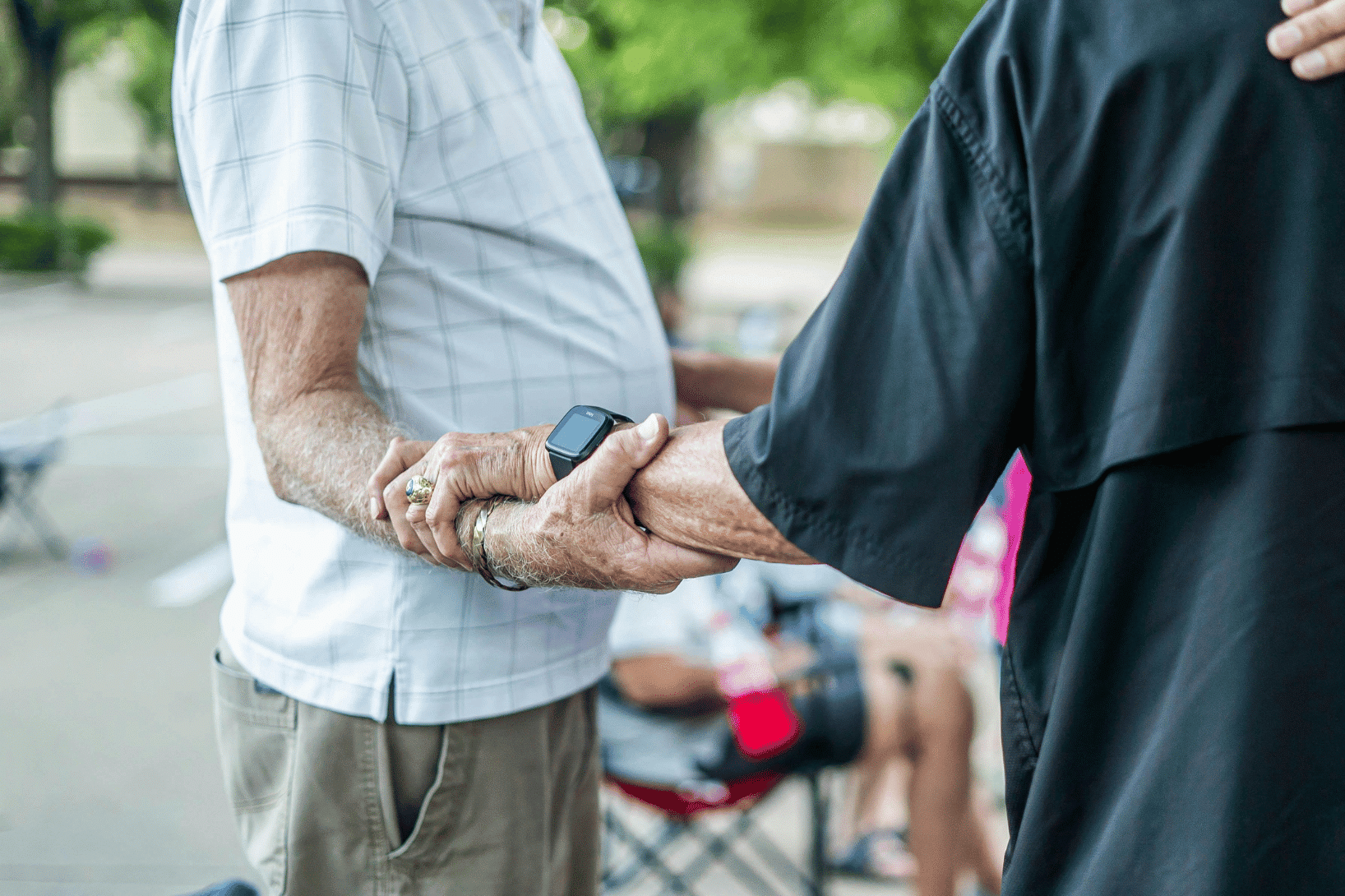 two elderly people embracing each other, one wearing a smartwatch