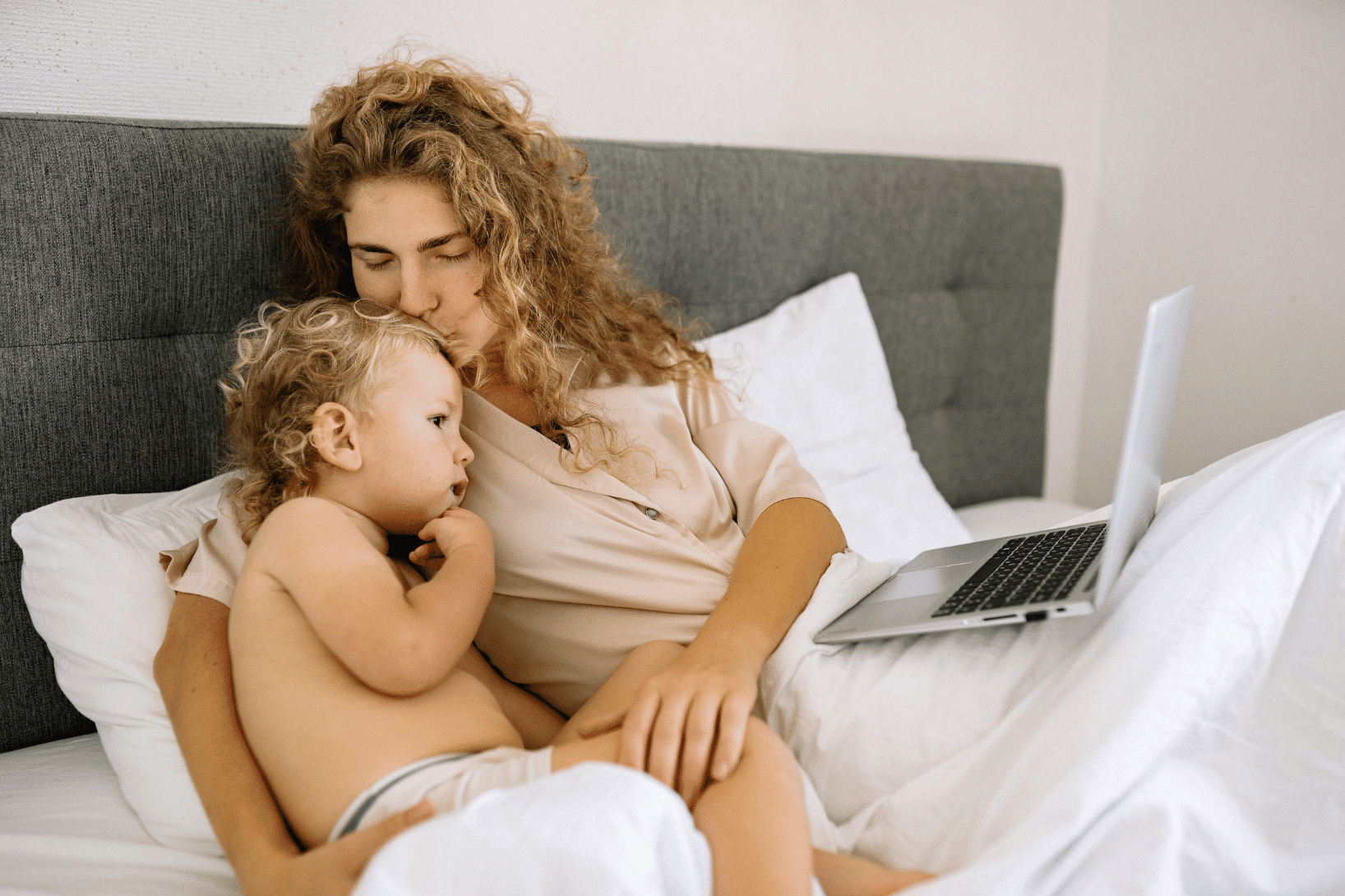 mom and child in bed together viewing laptop screen