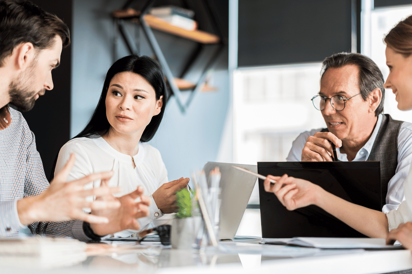 Four research professionals around table with laptops in a discussion